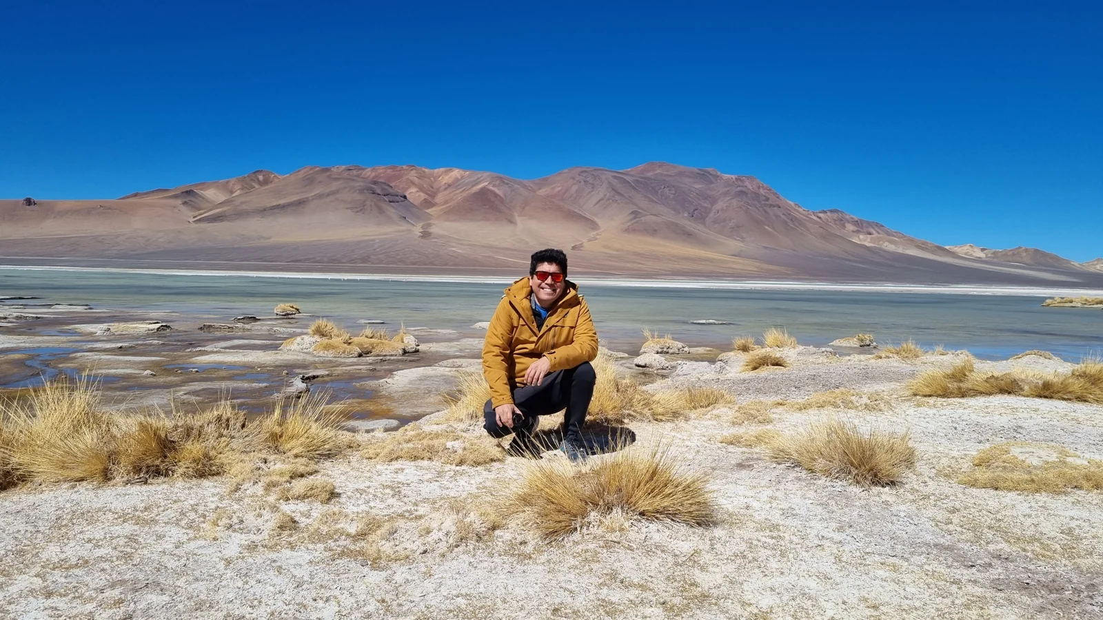 Hernan Caceres beside a high-altitude lake and mountains